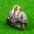 Miniature pink crystal handbag pendant with golden metal handle on green grass - Rhodonite