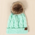 Detail of mint green cable knit beanie featuring a brown faux fur pom and a leather patch - One Size / Apple Green