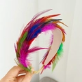 Close-up of vibrant multicolored feathers on a pink headband shown in hand - Green Multicolor Feather Headband