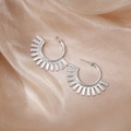 Elegant silver-tone sunburst earrings with a geometric ray design on champagne satin fabric - Silver Radiating Sun Earrings
