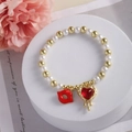 Bracelet de perles plaqué or 18 carats avec pendentifs lèvres et cœur sur support blanc - Pendentif Lèvres et Cœur à l'Huile (E)