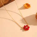 Detail of gold floral necklace with red gemstones on a minimalist textured surface - Gold Red Cat's Eye Necklace
