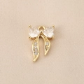 Macro shot of gold bow pendant with heart-shaped zircon inlay on woven fabric background - Double Heart Zirconia Bow (PJ0242) / Gold