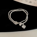 Macro detail of silver double-layer beaded bracelet with bell and peanut charm pendant - Double Layer Beaded Ruyi Bell Bracelet (WB1905) / Silver