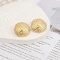 Detailed view of golden spiral woven stud earrings on a white rippled display plate - Gold EH011 (Vintage Woven Texture)