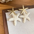 Detailopname van raffia en goudkleurige metalen zeester hanger oorbellen voor dames - 33# Goud-Wit (Zeester Oorknopje)