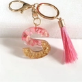 Detail of pink resin letter S keychain with gold foil flakes and matching tassel - Letter S