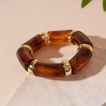 Nahaufnahme von Schildpatt-Resin-Armband mit polierten goldenen Metallringen - Kaffeebraun