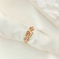 Detail view of a gold geometric ring with pink zircon stones on white silk fabric - Adjustable Open / Gold Color Pink Zirconia