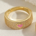 Détail d'une bague dorée ajustable avec pavé de zircons et motif de cœur en émail rose - Rose
