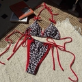 Sexy leopard print bikini set with contrasting red ties laid flat on a textured rug - Red