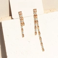 Golden asymmetrical long tassel earrings with orange cubic zirconia on a jewelry card - 18K Gold / Champagne