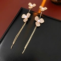 Detailed close-up of gold clover earrings with pavé crystals and long fringe chains - Gold
