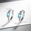 Detalle macro de aretes de aro plateados con piedra azul ovalada y circonitas brillantes - Zirconia Azul Cielo