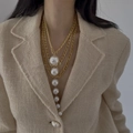 Elegant multi-layer gold chain necklace with cascading pearls on a tweed outfit - Gold-White