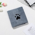 Close-up of thick grey coral fleece towel with a black paw print embroidery for pets - Gray