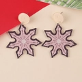 Macro detail of pink glitter snowflake earrings with black outline and elegant ear hooks - Snowflake