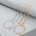 Détail de parures de bijoux chaîne trombone argent et or avec fermoirs à bascule sur gris - Type B 5mm / Collier 60cm / Doré