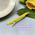 Detalle de una pinza para el pelo creativa con forma de lápiz amarillo y punta de madera - Amarillo