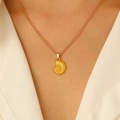 Dettaglio di una collana con ciondolo a conchiglia dorata indossata su scollo bianco - Collana a catena sottile con ciondolo a forma di nautilus dorato