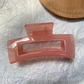Close-up of a pink jelly resin rectangular hair claw clip on white textured paper - Jelly Pink