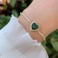 Dettaglio di un bracciale placcato oro 18 carati con zircone cuore verde sul polso - Verde
