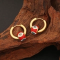 Golden hoop earrings with red evil eye charms displayed on rustic wood background - Red