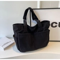 Detail of black corduroy tote bag showing textured fabric and front pocket design - Black