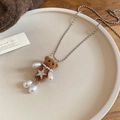 Detail of brown flocked bear pendant with pearl and star on a ceramic jewelry tray - Flocked Bear Teardrop Star Necklace