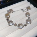 Dettaglio del bracciale con perline e fiocco di neve in un portagioie di velluto crema - Stile con Perline a Fiocco di Neve / Argento-Bianco