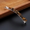 Detailed close-up of Tiger Eye crystals on a metal hair clip over a dark wood tray - Tiger Eye with Silver Clip