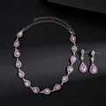 Detalle del colgante de gota púrpura y pendientes con halo de diamantes sobre fondo negro - Morado
