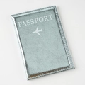 Macro detail of silver-blue metallic leather passport cover with white embossed text - Light Blue