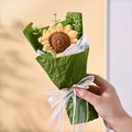 Close-up of a hand-knitted sunflower bouquet with green paper wrapping and a white silk ribbon - Single Knitted Sunflower / 13x22cm