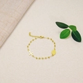 Detail of gold beaded bracelet with a cross charm and religious medal on a soft surface - Gold Priest