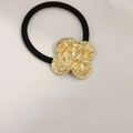 French minimalist hair tie with a textured golden metallic flower and black elastic band - Lava Rock Clover Gold