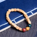 Macro detail of wooden bead bracelet with colored accents on a vintage blue book - 7mm Three Colors Sugar Cube / New Mountain Sandalwood Color