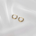 Close-up of gold hoop earrings with black enamel geometric pattern on white silk fabric - Black