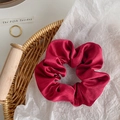 Detail shot of a deep red satin scrunchie with rich folds and pearly silk texture - Red