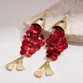 Pendientes dorados en forma de pez con escamas rojas de concha sobre mármol - Rojo