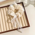 Beige floral lace scrunchie with elegant long ribbons on a wooden jewelry tray - White Ribbon Lace