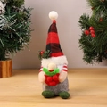 Dettaglio dello gnomo natalizio in peluche con cappello a quadri e bacche su legno - Ornamento di Gnomo Babbo Natale in Piedi