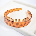 Macro view of leopard print plastic headband with teeth on a beige jewelry tray - 5# Wide Leopard Print Toothed Headband