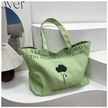Dettaglio della borsa tote in tela verde con stampa floreale nera e design studio NKK - Verde