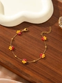 Detail of 18K gold-plated beaded floral bracelet with lobster clasp on wooden background - Rose and Orange