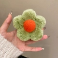Detail view of plush flower hair claw featuring green petals and a soft orange center - Green