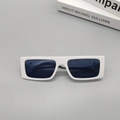 Detail van witte vierkante zonnebril met donkere glazen op een grijze minimalistische basis - Porselein Wit