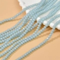 Macro shot of 4mm light blue faceted rondelle glass beads on a vintage white plate - Opal Light Blue