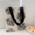 Detail of floral knit tote bag featuring a magnetic snap closure and black wide handles - Rope Texture