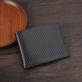 Cartera bifold de hombre con textura de fibra de carbono negra sobre fondo de madera - Negro